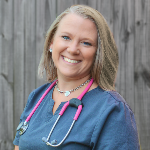 A blonde women smiling brightly at the camera, wearing a pink stethoscope.