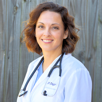 Headshot of a smiling brunette veterinarian wearing a stethoscope and coat.